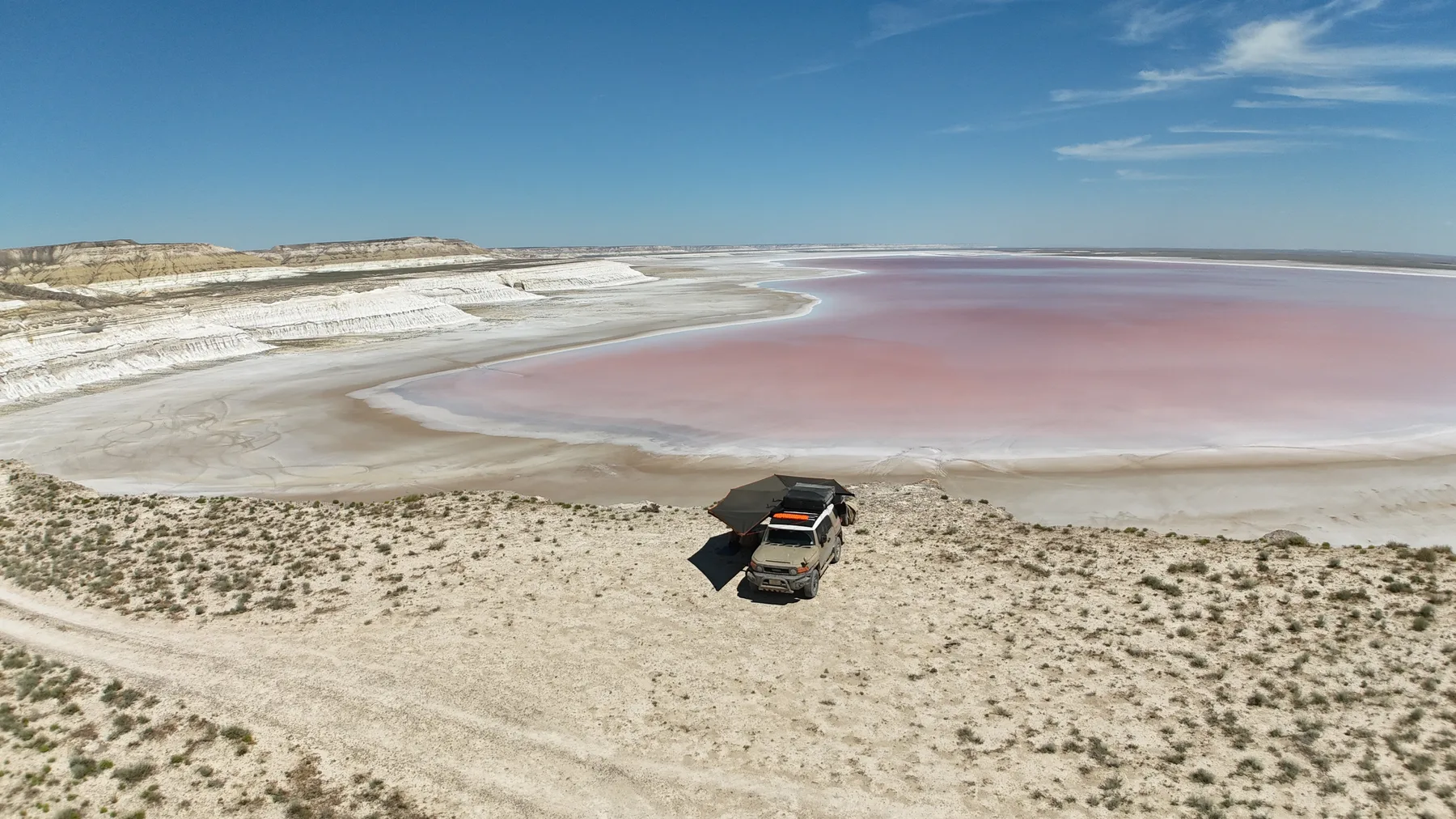A white salt pan stretching to a line of chalk cliffs with a natural arch.